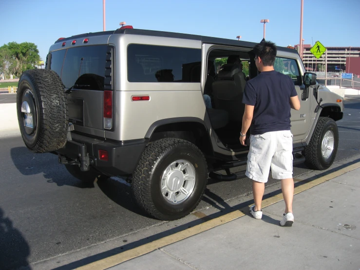 a man standing next to a jeep with large tire rims