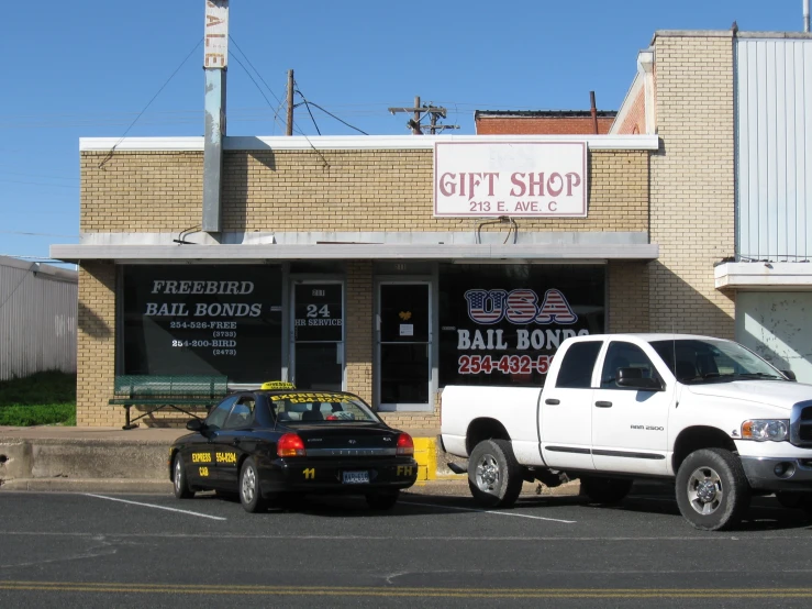 two trucks parked outside the storefront of a brick building