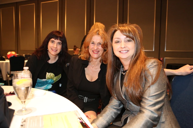 three woman sitting at a table in a conference center