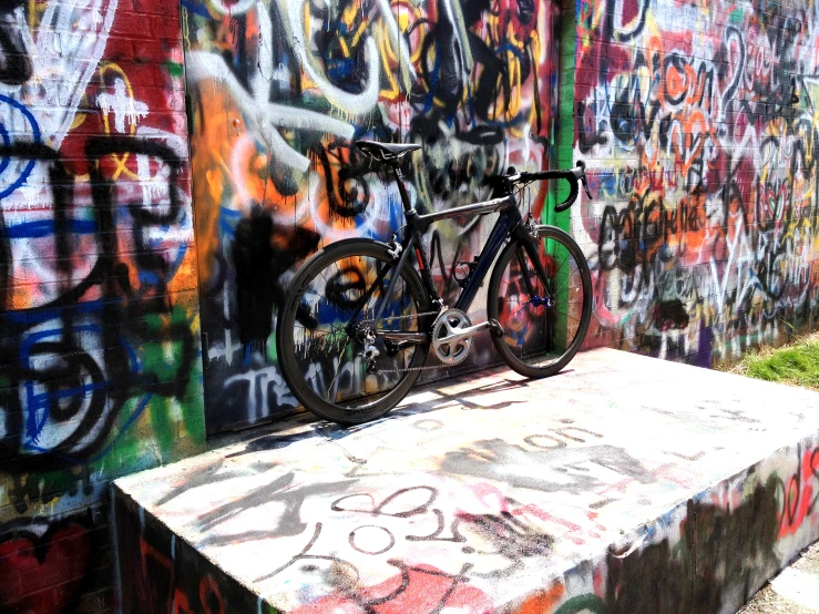a bicycle parked on a concrete slab in a graffiti covered park