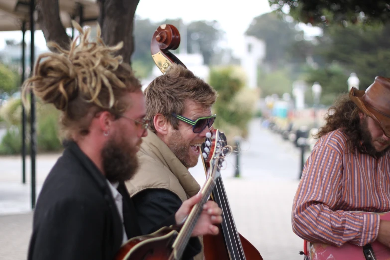 a group of men are outside playing guitars