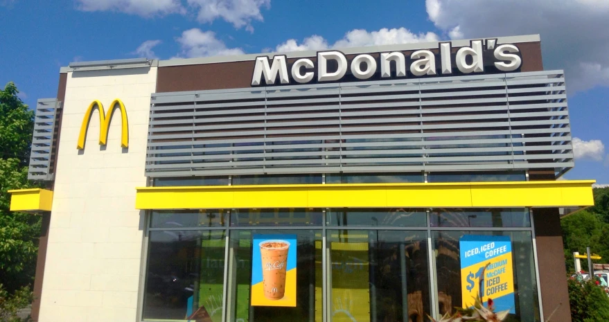 a mcdonald's restaurant sitting on a street corner with its window glass partially closed