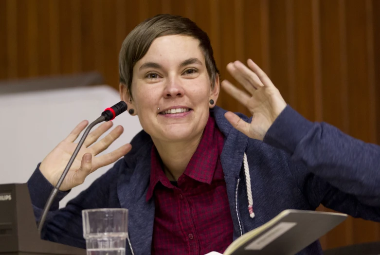 a woman sitting at a table with a book on the table and microphone