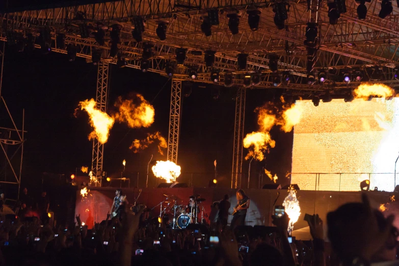 a crowd at an outdoor concert with a huge screen showing fireworks