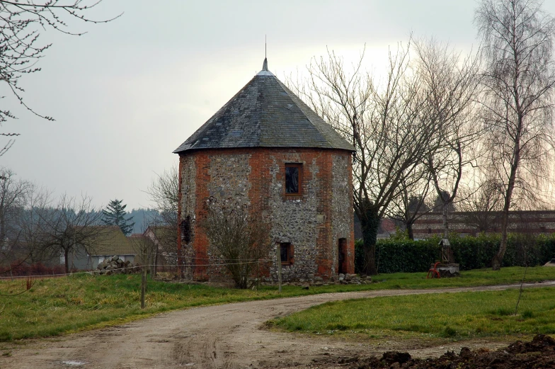 an old brick building that is standing in a field
