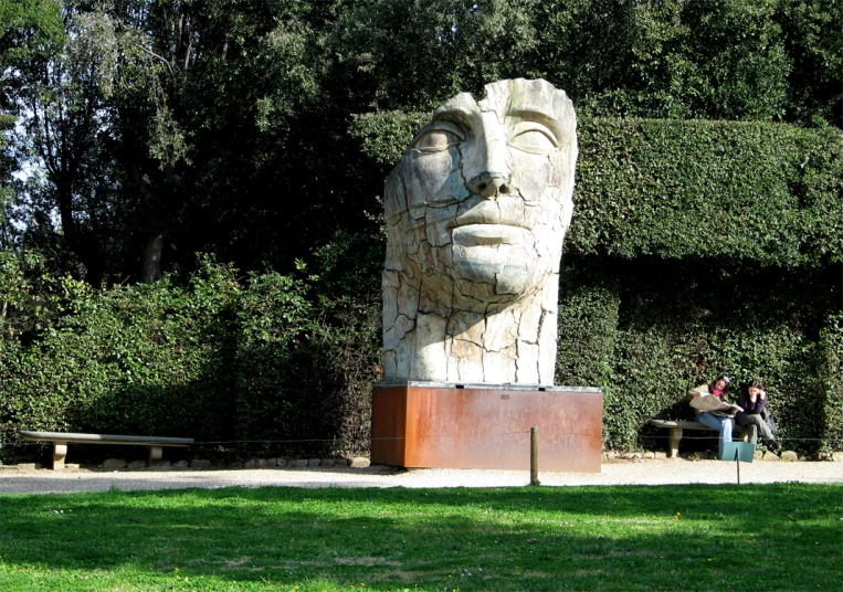 a man sitting on a park bench next to a statue