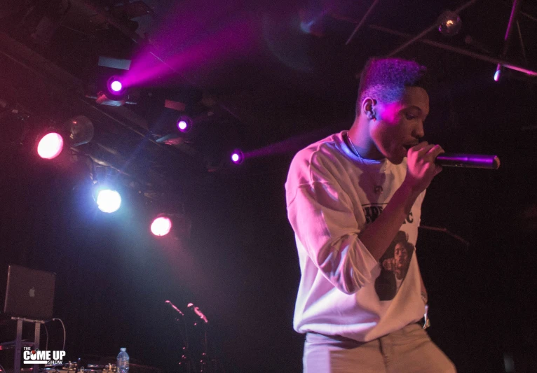 a black man singing into a microphone while another looks on