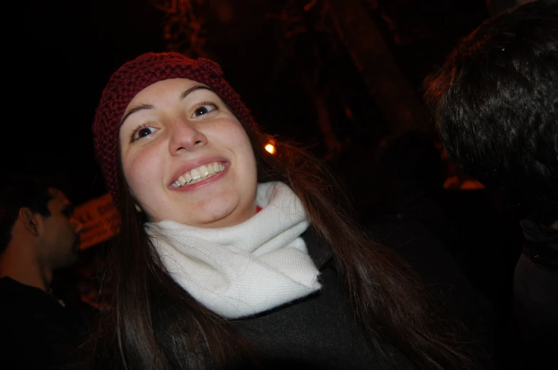 a woman in a hat smiling while wearing a scarf