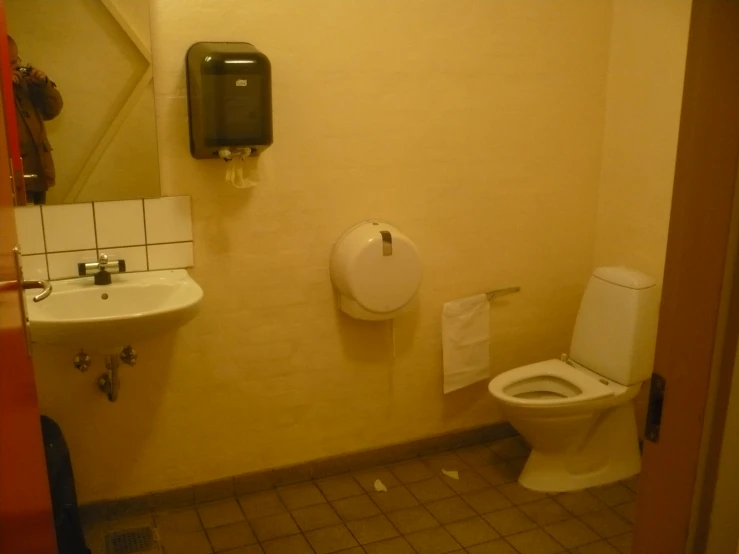 a bathroom with a toilet, sink and mirror