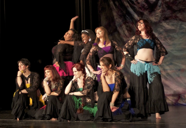 a group of ladies in dresses and tuxedos at a fashion show