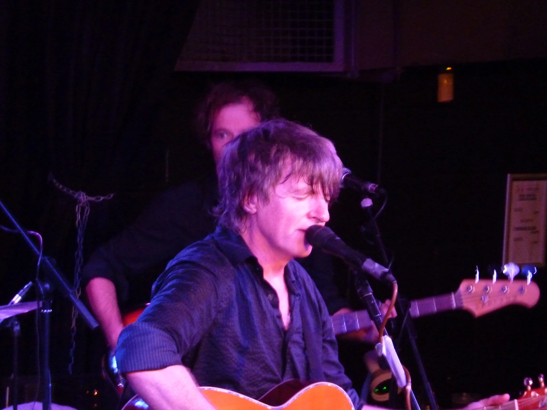 a person singing and playing guitar in front of a microphone