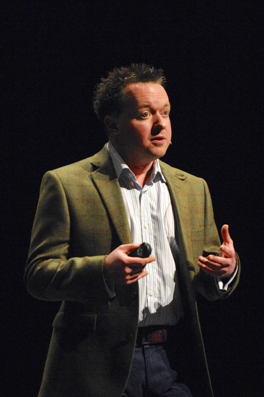 a man with hands wide open, speaking on stage