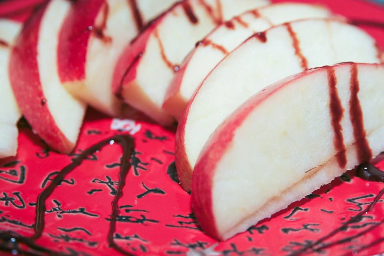 sliced apples on red dish with chocolate sauce