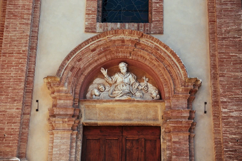 large statue above an entrance way near brick wall