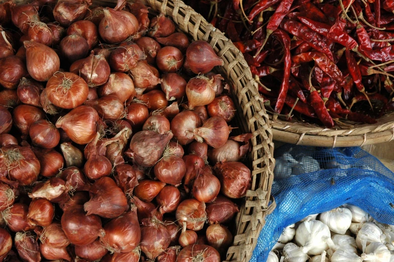 baskets full of onions and garlic are in various bowls