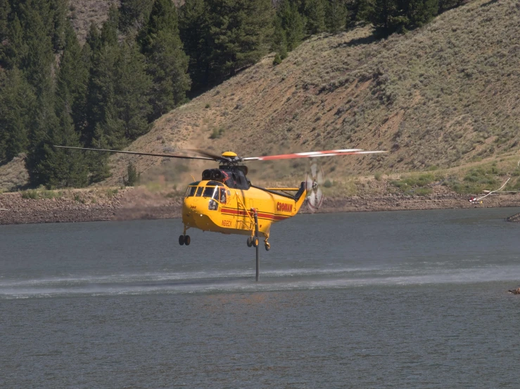 a yellow helicopter flies over some water