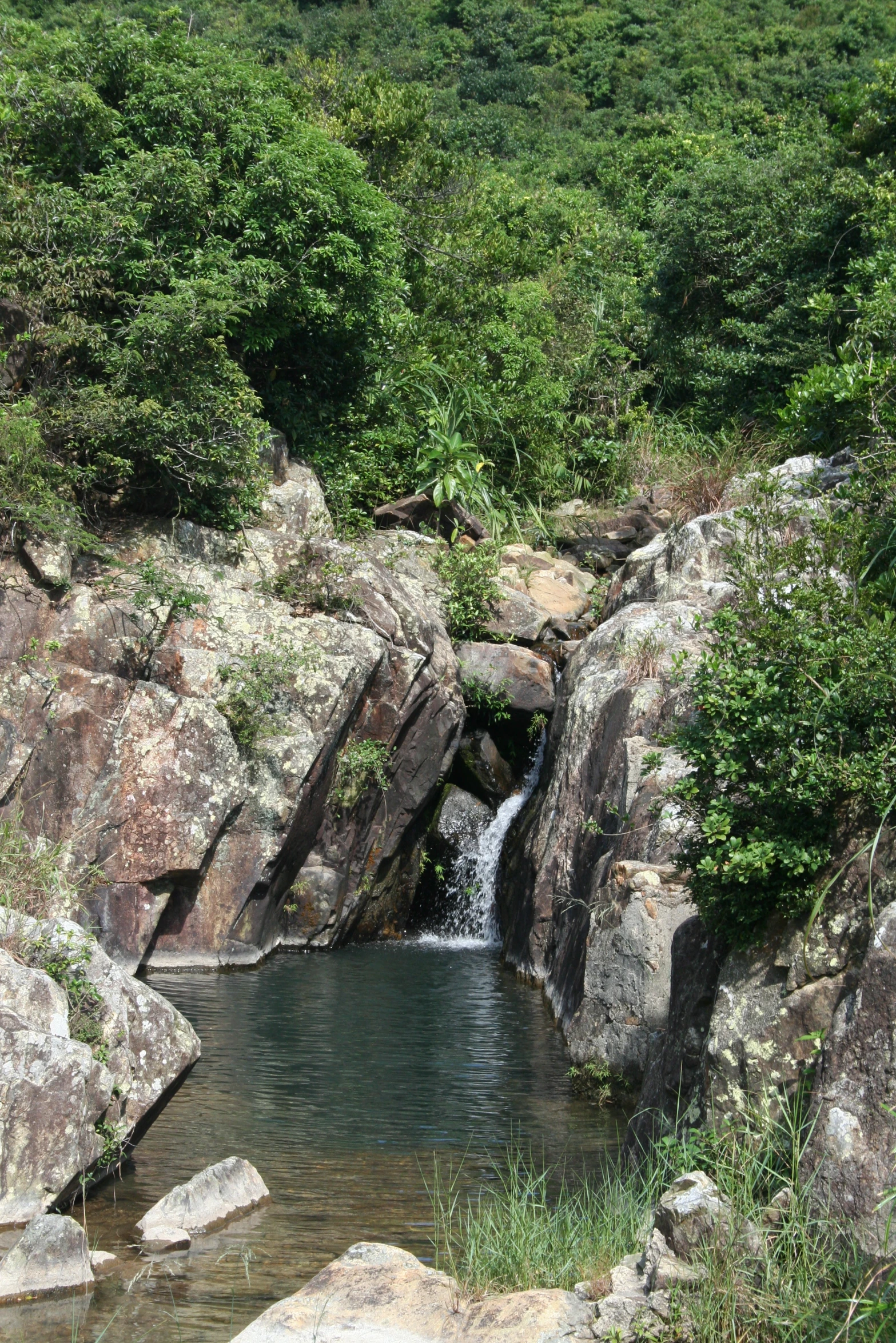 a water fall surrounded by green mountains and rocks