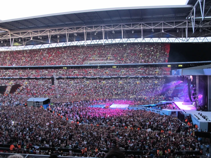 a crowd at a concert sitting in a large stadium