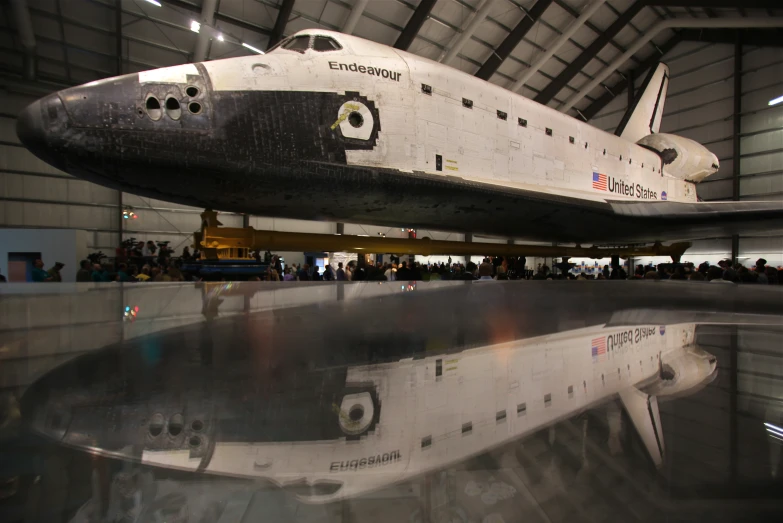 people are gathered in a museum looking at a space shuttle