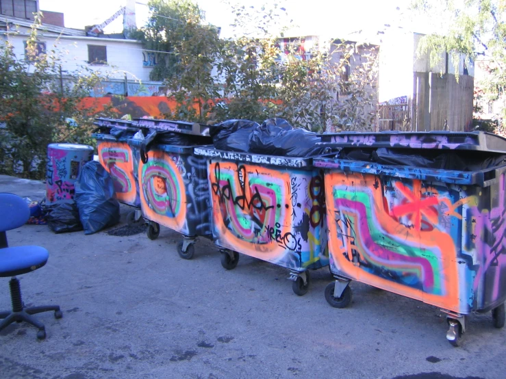 a bunch of trash cans that have graffiti on it