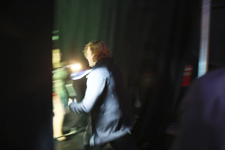 a man with red hair and a coat walks down a dark alley way