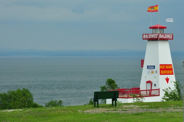 a white and red light house on the water with flagpole