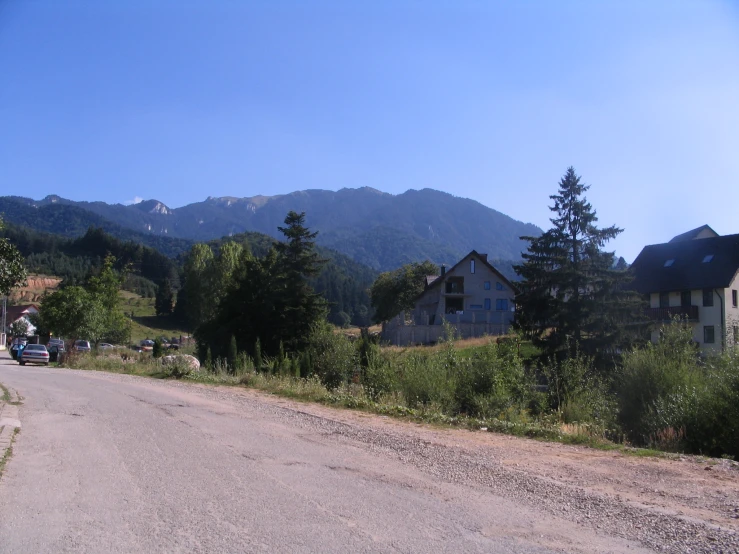 a small dirt road between two houses in the mountains