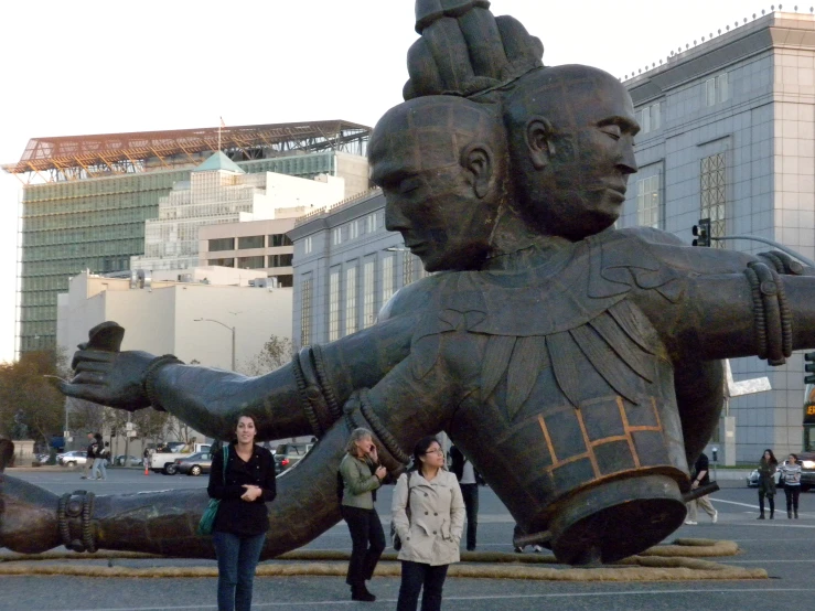 two people walking in front of a large sculpture