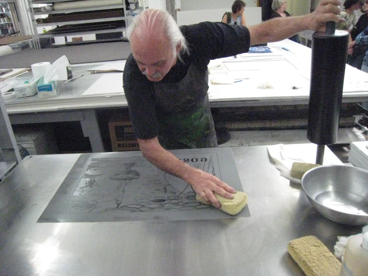 a man standing in a kitchen using a sponge