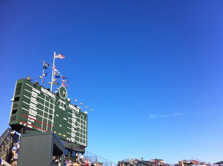 many spectators are gathered outside in front of the scoreboard