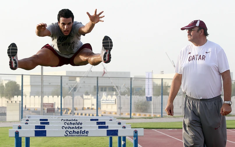 the man is jumping over a hurdle in the middle of his body