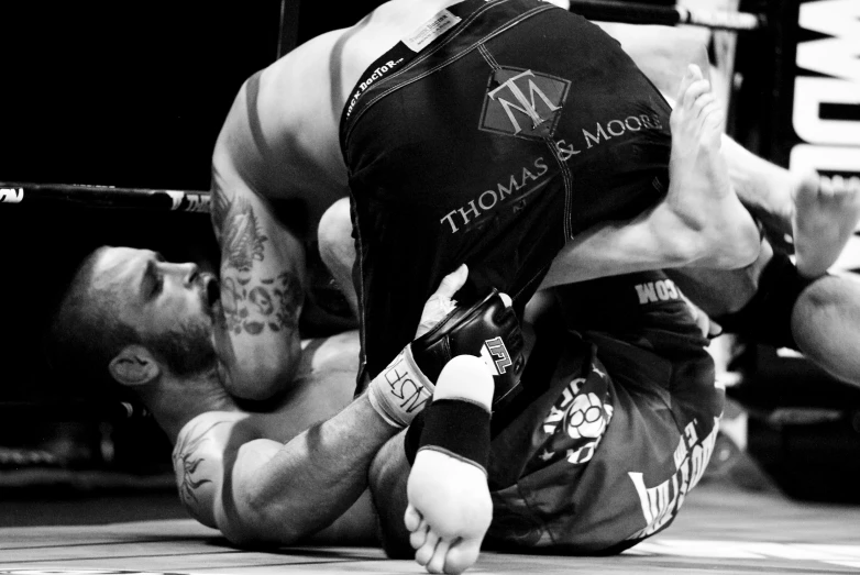 a man that is sitting on the ground holding a wrestling