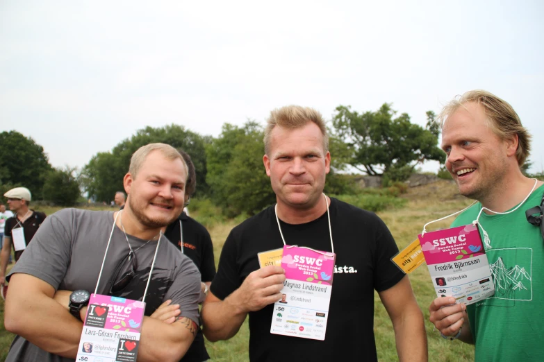 two men holding up tickets with a grass background