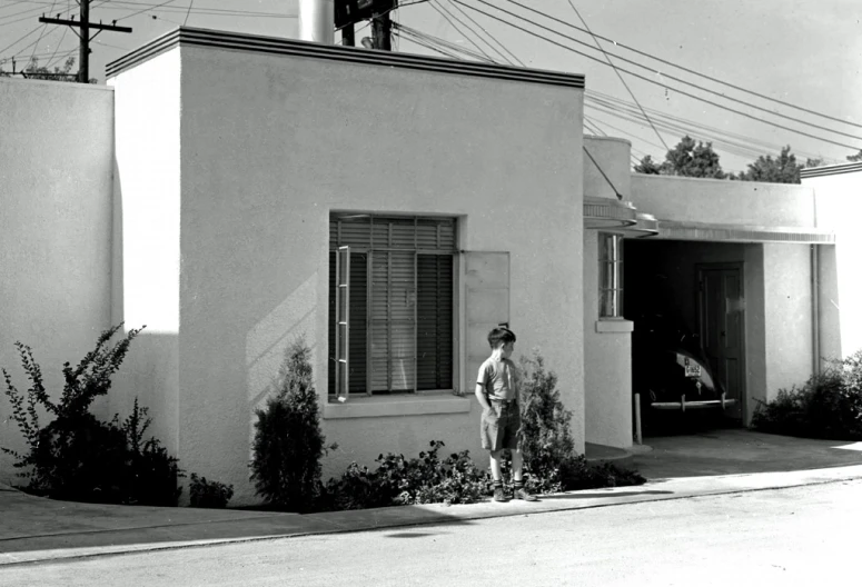 the boy is standing in front of his house