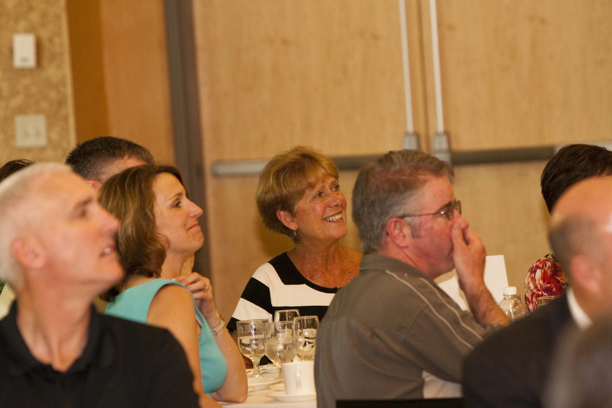 a large group of people sitting at tables with glasses on top of them