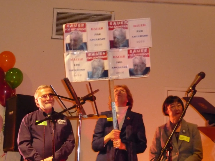 two people singing with microphones and a poster in the background