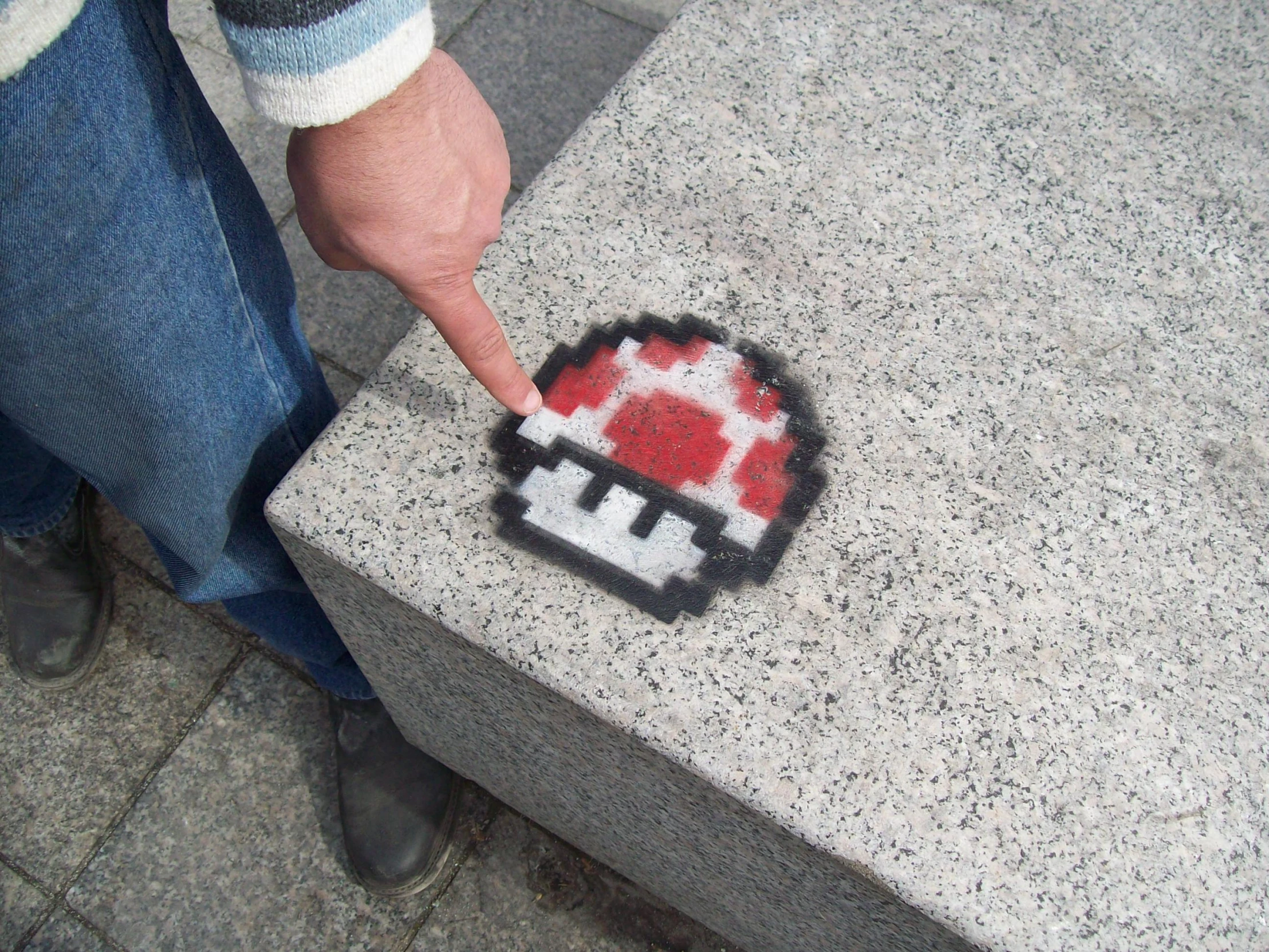 a man putting his finger in the center of a picture on a sidewalk