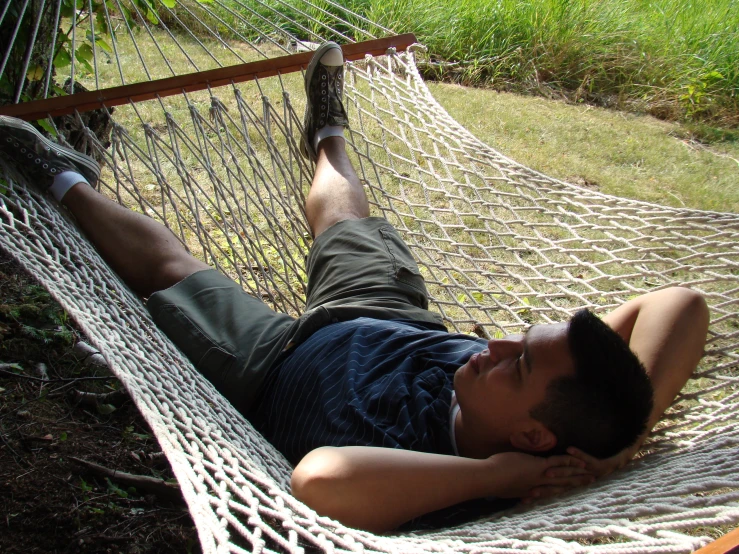 a man laying in a hammock on the grass