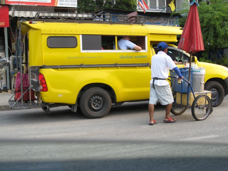 an odd looking yellow truck with two people standing on the side of it