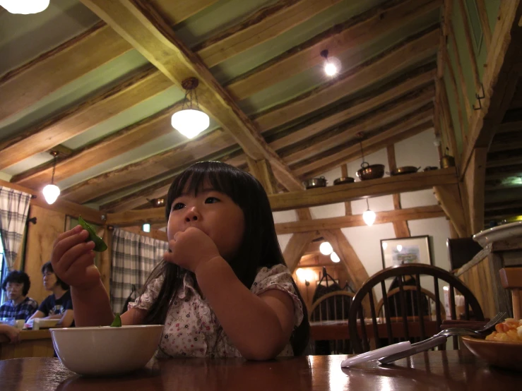 a little girl eating food on top of a bowl