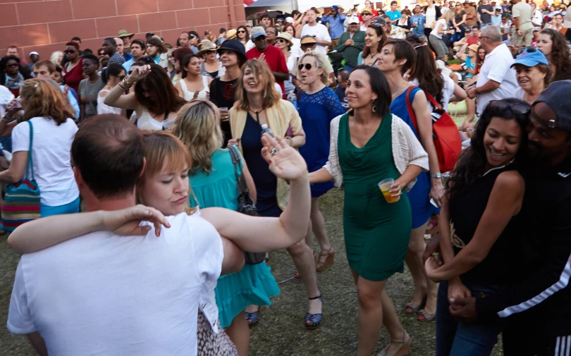 a crowd of people in a field are dancing