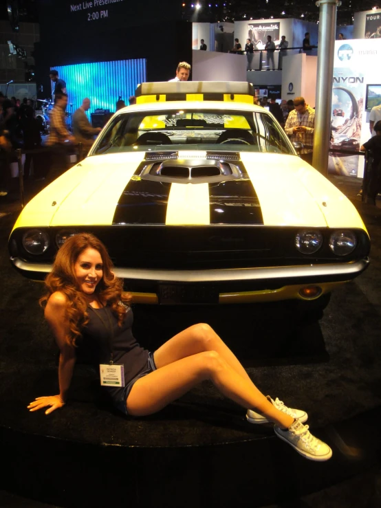 a woman posing in front of an old - school car