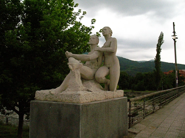 a statue sitting on a cement slab near a tree