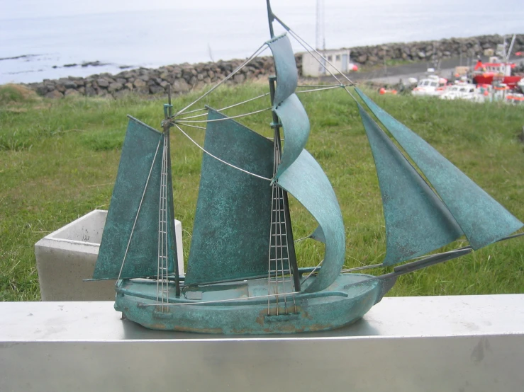 a statue of a sailboat on some grass