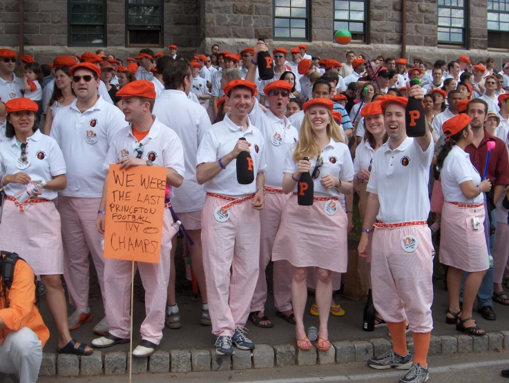 a group of people in matching orange and white outfits hold a sign that says, we're there for team orange