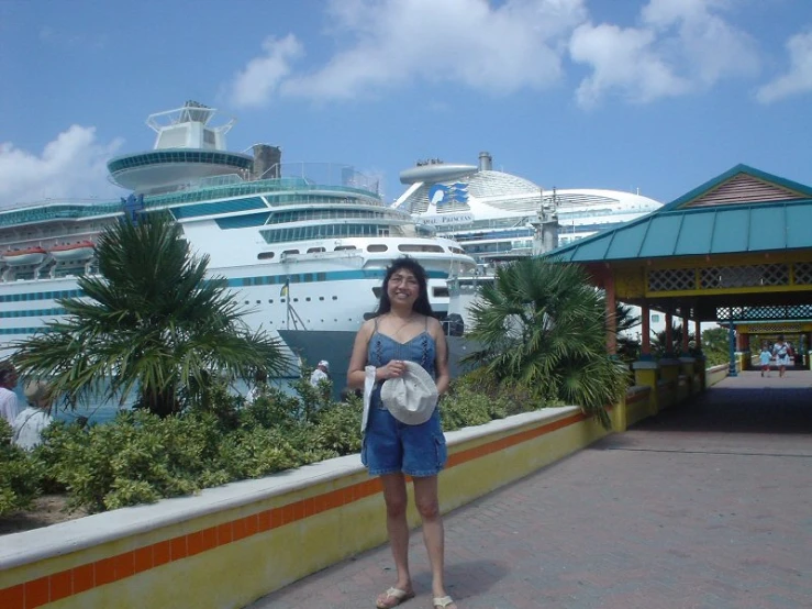 a woman standing on a stone wall near two cruise liners