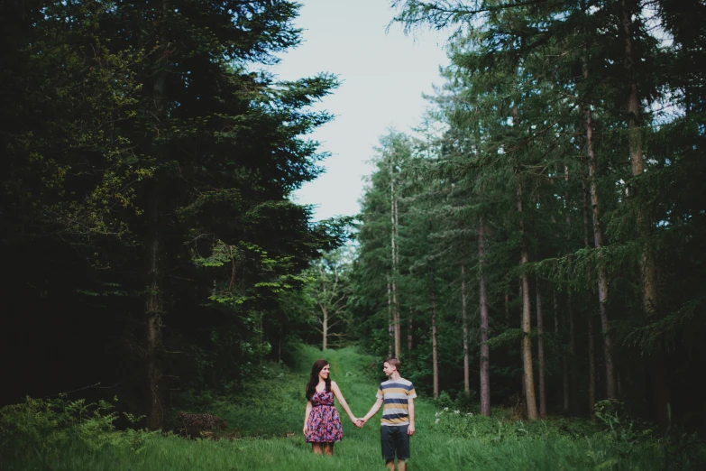 two people holding hands as they walk through the woods