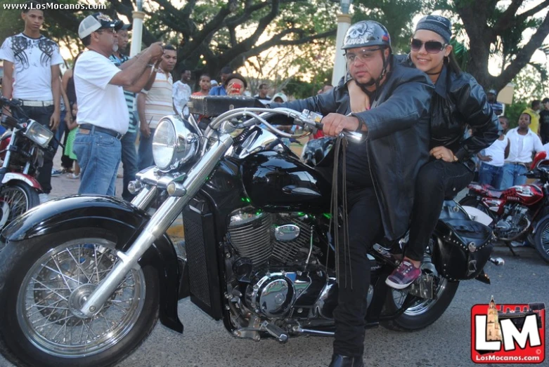 two men pose for a po while on a motorcycle