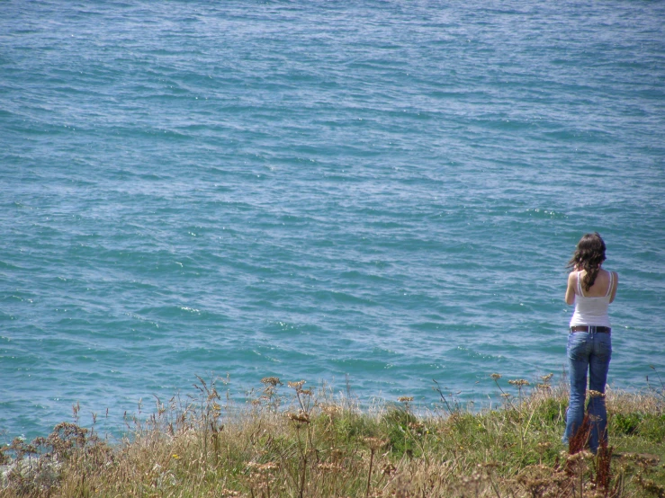 a person standing on a ledge next to the ocean