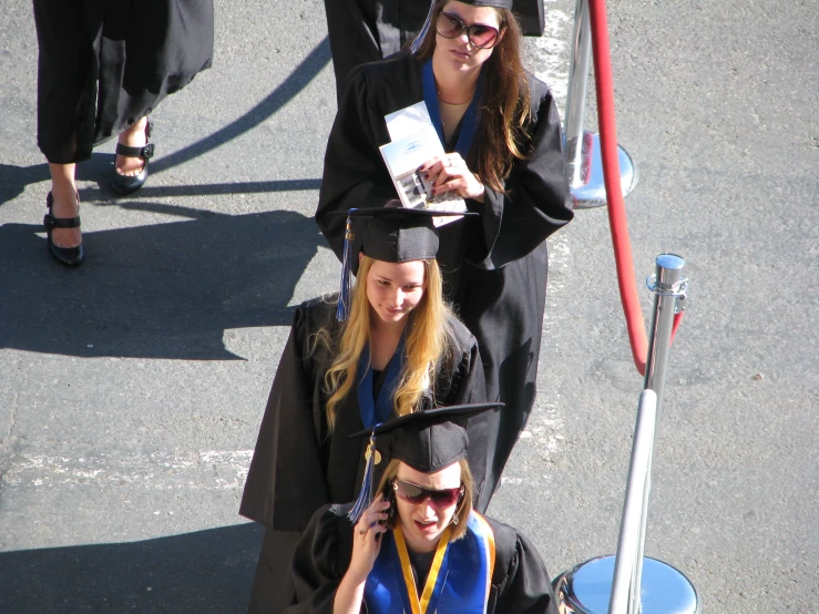 three women in graduation robes stand in a row and talk